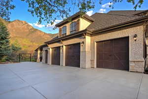 View of front of home with stucco siding, driveway, a mountain view, and stone siding