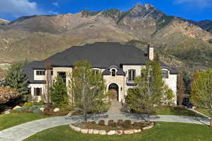 French country inspired facade with stone siding, a front yard, a mountain view, and a chimney