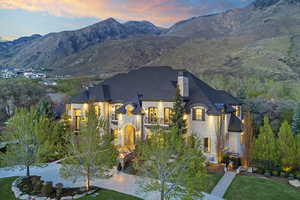 French country style house featuring a chimney, a mountain view, a lawn, and stone siding