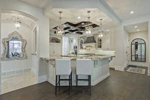 Kitchen with light stone countertops, white cabinetry, hanging light fixtures, decorative backsplash, and a breakfast bar area