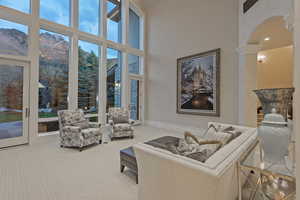 Living room featuring a mountain view, arched walkways, light colored carpet, a high ceiling, and ornate columns