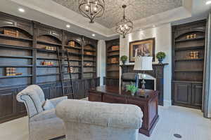 Carpeted office space featuring built in features, hanging lights, and a raised ceiling