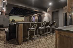 Home theater room featuring dark carpet and a community bar