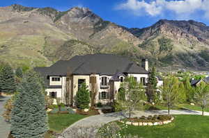 View of front of property with a mountain view, a front yard, a chimney, and stone siding