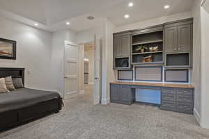 Bedroom featuring light colored carpet, built in desk, and recessed lighting