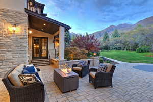 Patio / terrace featuring french doors, an outdoor living space with a fire pit, a lawn, a patio, and a mountain view