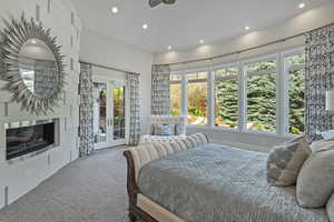 Carpeted bedroom with french doors, access to outside, a glass covered fireplace, and recessed lighting