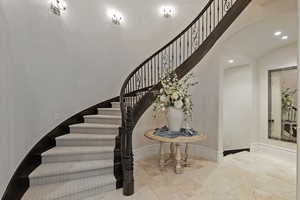 Stairs with recessed lighting, stone tile flooring, and arched walkways