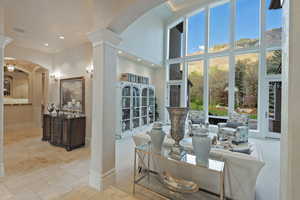 Living area featuring arched walkways, a high ceiling, decorative columns, and stone tile flooring