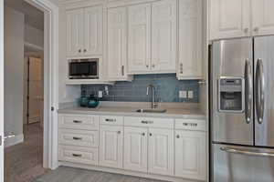 Kitchen featuring stainless steel appliances, decorative backsplash, and white cabinetry