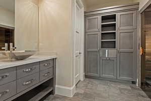 Bathroom featuring vanity, a closet, and light stone finish floors
