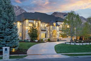 French provincial home with stone siding, a yard, a balcony, and a mountain view