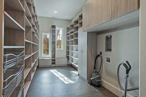 Walk in closet with dark wood-style floors