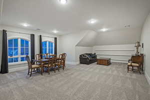 Dining area featuring light carpet and vaulted ceiling