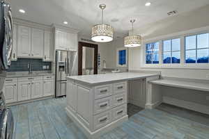 Kitchen featuring wood tiled floors, stainless steel refrigerator with ice dispenser, light countertops, and washer / clothes dryer