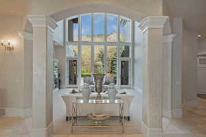 Living area featuring ornate columns, a high ceiling, light carpet, and recessed lighting