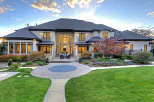 Rear view of property with a patio area, stucco siding, a standing seam roof, roof with shingles, and stone siding