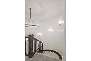 Stairway with carpet flooring, a chandelier, and a raised ceiling