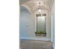 Hallway featuring carpet flooring, arched walkways, and vaulted ceiling
