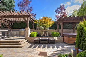View of patio with a pergola, area for grilling, and a hot tub