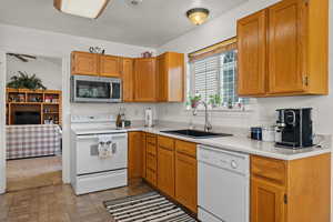 Kitchen featuring white appliances, light countertops, wood finish cabinets, and brick patterned floors