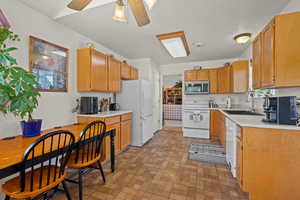 Kitchen with light countertops, white appliances, ceiling fan, and brick patterned floors