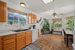 Kitchen with light countertops, dishwasher, brick patterned floors, ceiling fan, and wood finish cabinetry