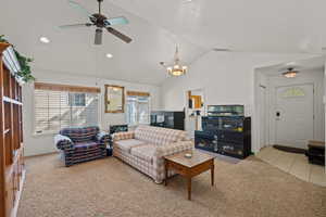 Living room with light colored carpet, a ceiling fan, and suspended lighting