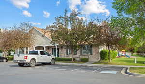 View of front facade featuring brick siding, uncovered parking, and a front lawn
