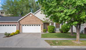View of front of house with driveway, a front yard, an attached garage, and brick siding