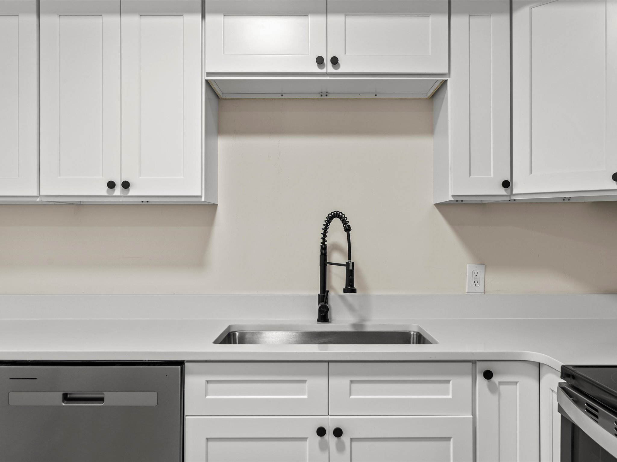 Kitchen featuring white cabinets, stainless steel dishwasher, and electric range