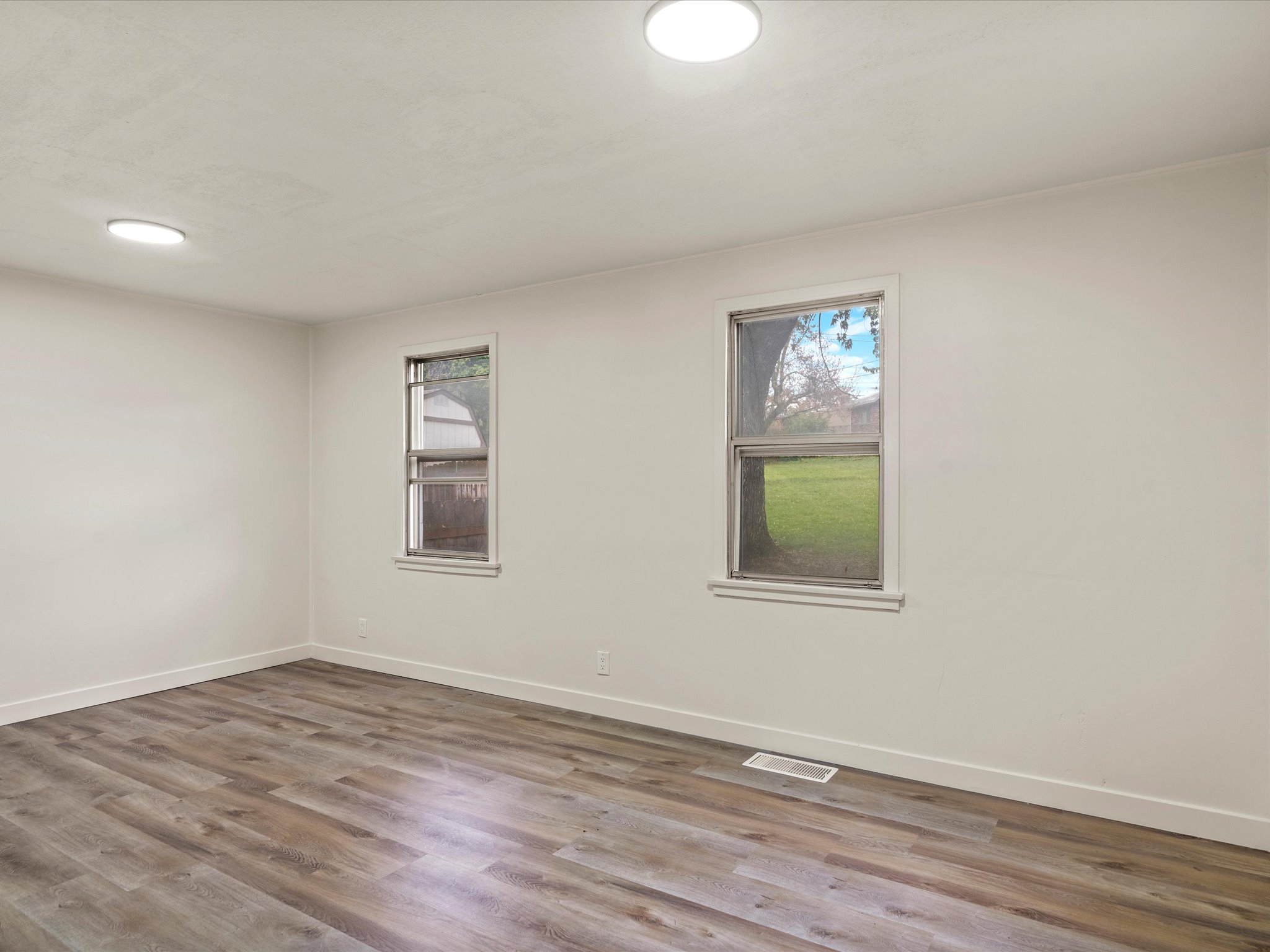 Spare room with dark wood-style floors and plenty of natural light