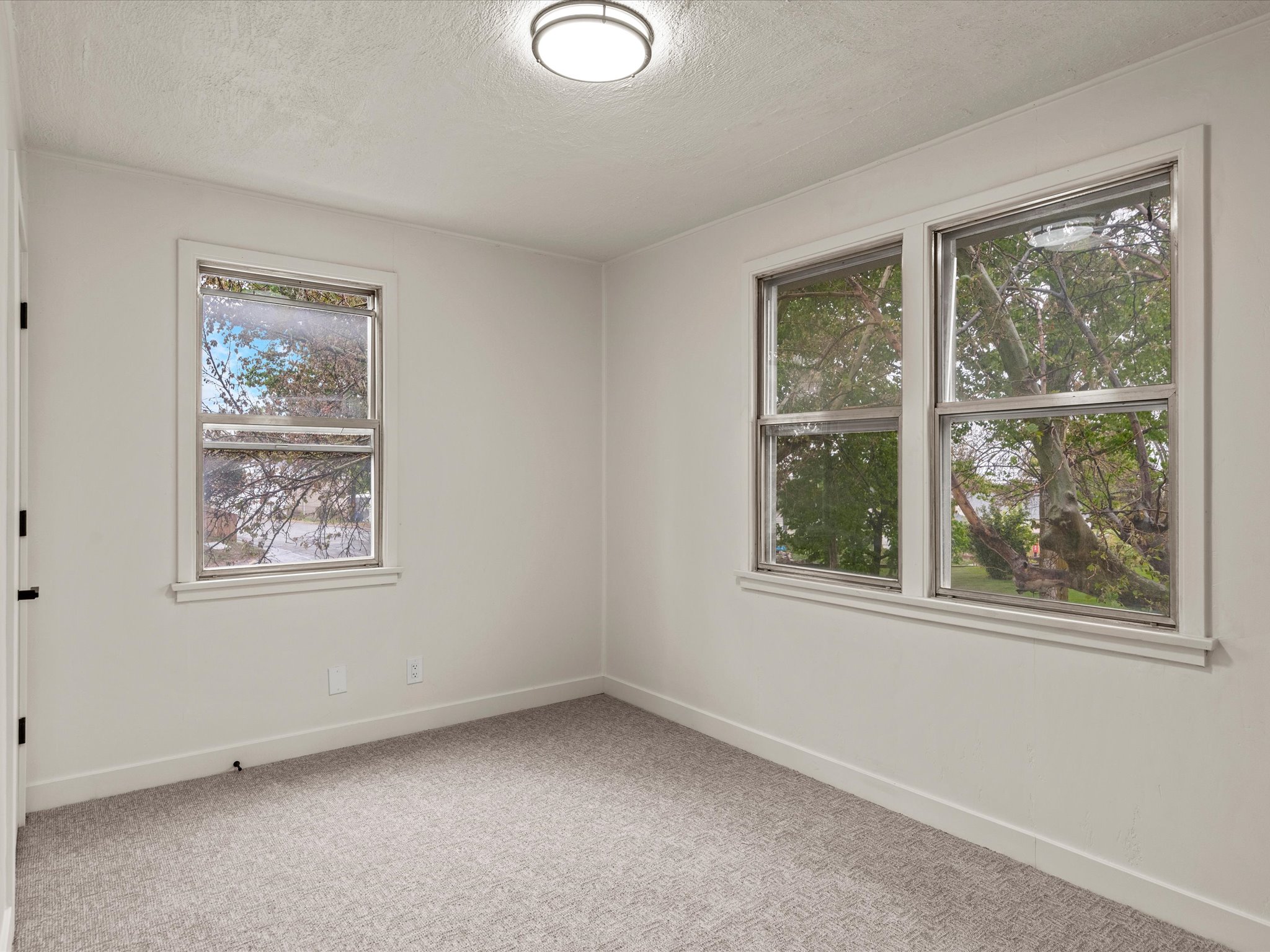 Empty room with light colored carpet and a textured ceiling
