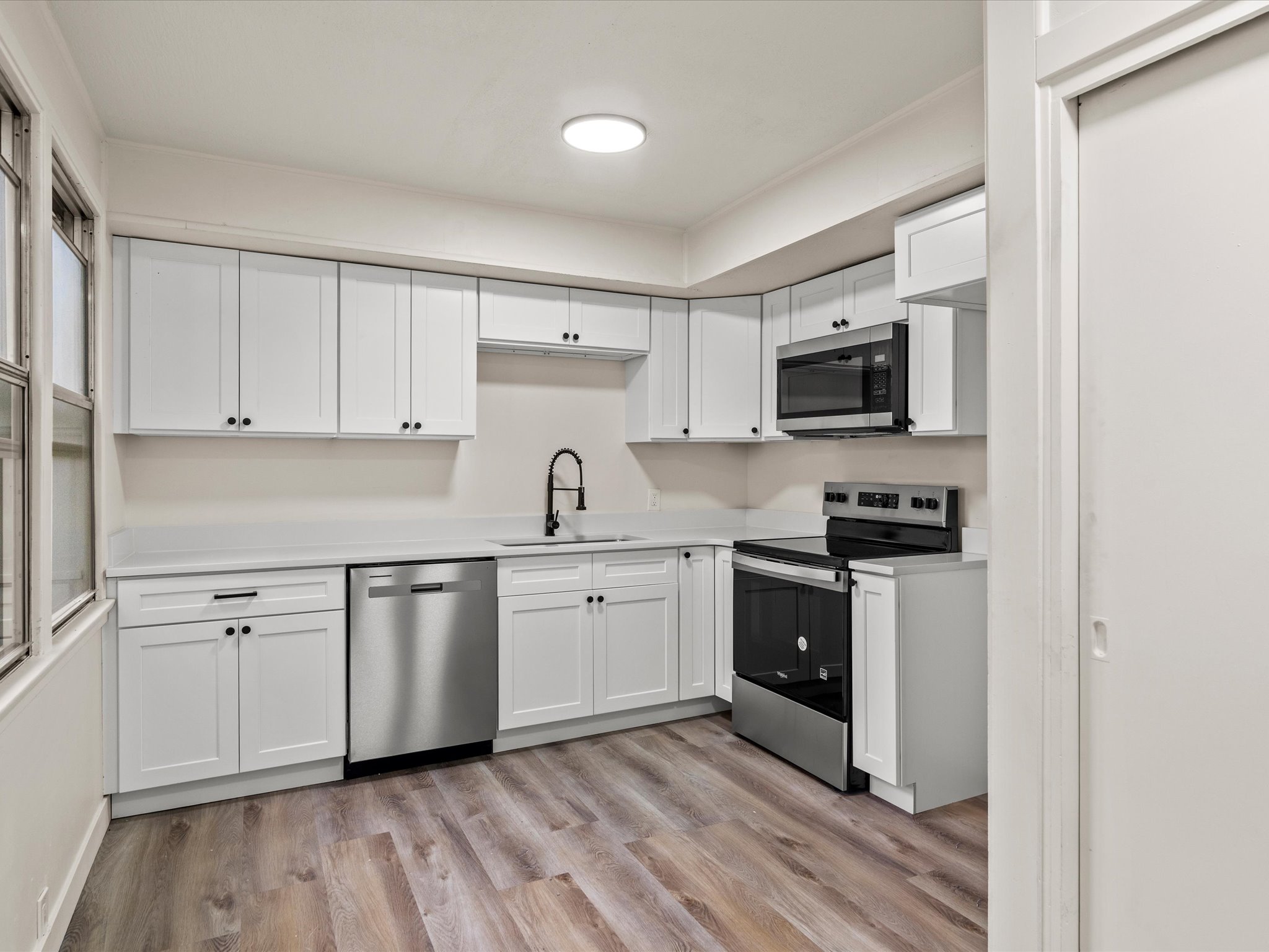Kitchen featuring white cabinetry, stainless steel appliances, light countertops, and light wood finished floors