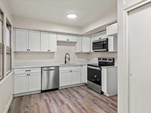 Kitchen featuring white cabinetry, stainless steel appliances, light countertops, and light wood finished floors