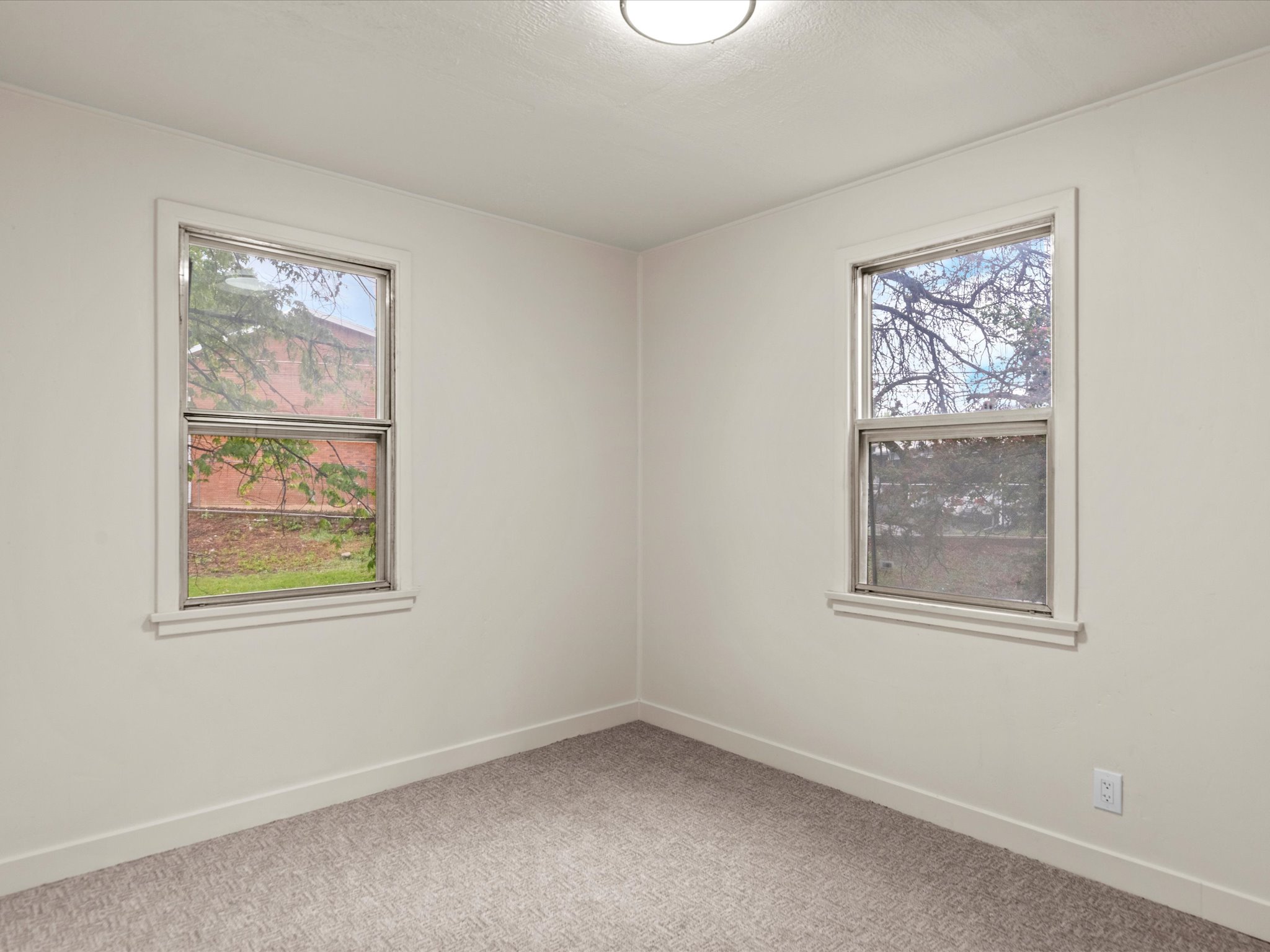 Empty room with light colored carpet and baseboards