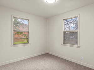 Empty room with light colored carpet and baseboards