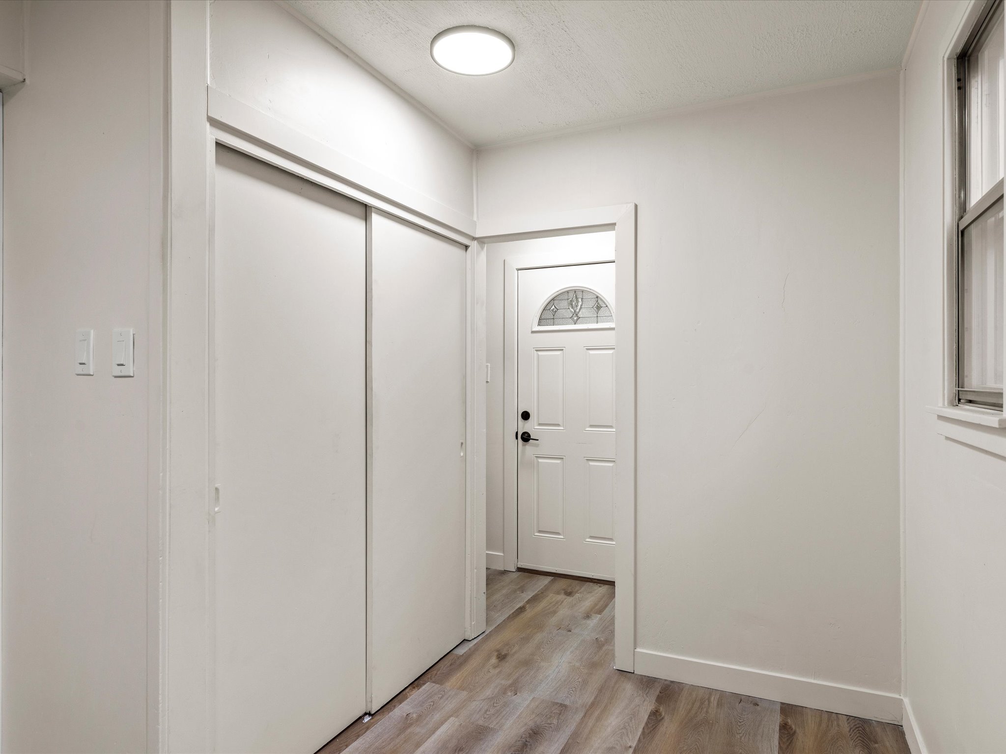 Foyer entrance with light wood-style floors and a textured ceiling