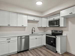 Kitchen featuring white cabinets, stainless steel appliances, and light countertops