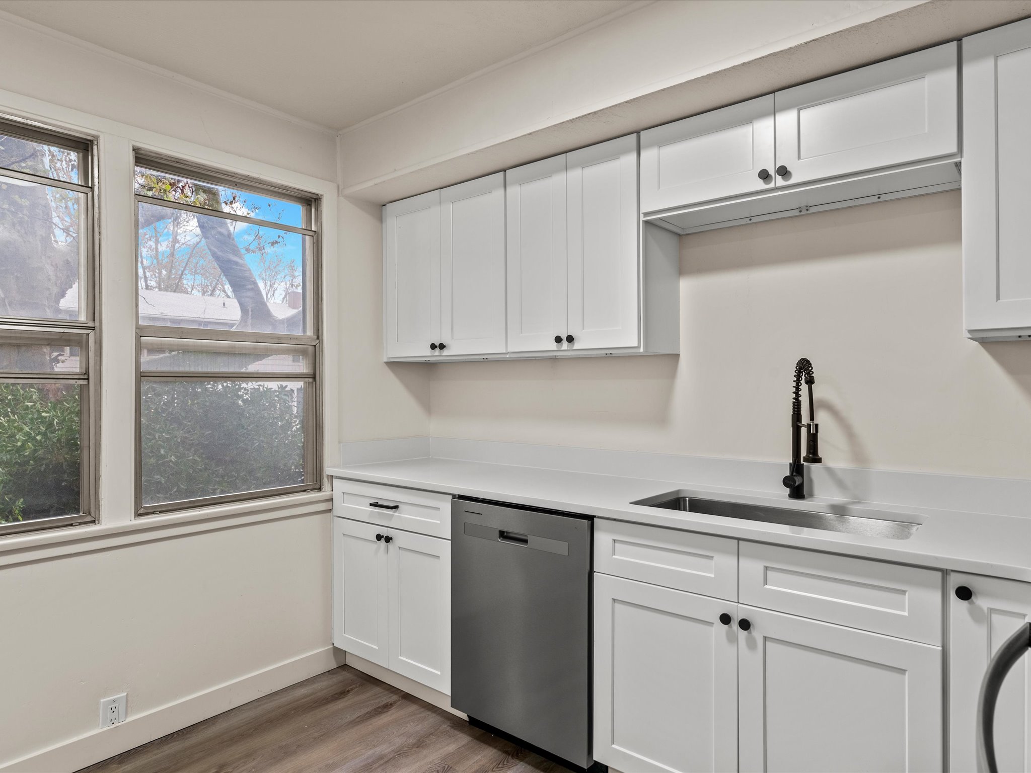 Kitchen featuring white cabinets, dishwasher, and dark wood-style floors