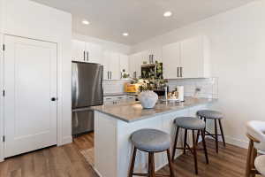 Kitchen featuring white cabinetry, a breakfast bar area, stainless steel appliances, a peninsula, and dark wood finished floors