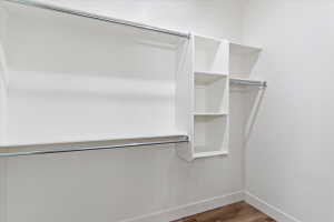 Walk in closet with dark wood finished floors