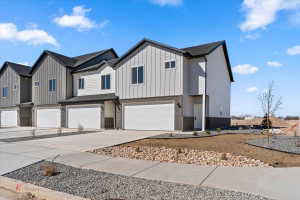 Modern inspired farmhouse featuring brick siding, a garage, board and batten siding, concrete driveway, and a residential view