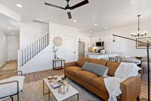 Living room featuring light wood-type flooring, ceiling fan, and hanging lights