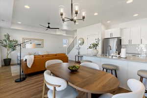 Dining space with suspended lighting, ceiling fan, and dark wood-style floors