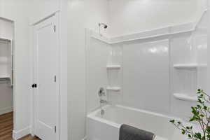 Full bath with bathtub / shower combination, a closet, and wood finished floors