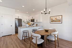 Dining area with light wood-style flooring and suspended lighting