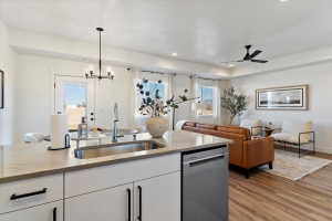 Kitchen featuring white cabinetry, light stone countertops, stainless steel dishwasher, and open floor plan