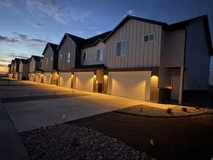 Modern inspired farmhouse with board and batten siding, an attached garage, brick siding, and concrete driveway