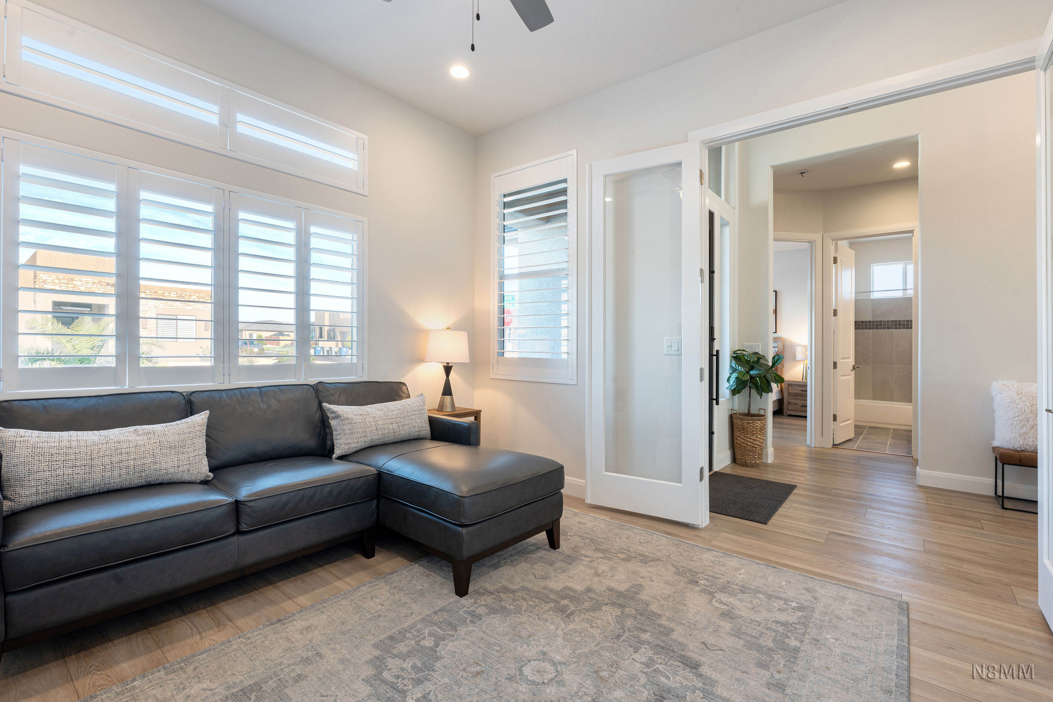 Living area with light wood-style flooring, ceiling fan, and recessed lighting